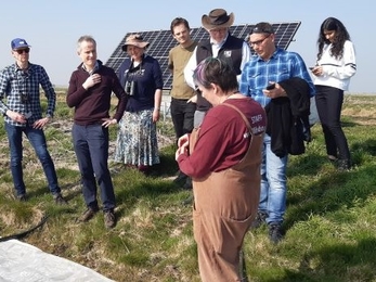 Group of adults stood on grass in front of a solar panel