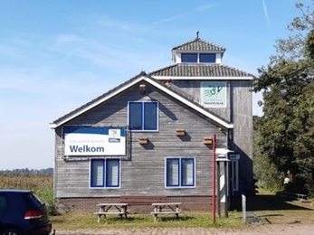 A wooden clad building with a Welkom sign