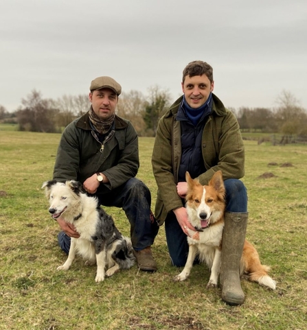 Craig and Ryan crouch with their sheepdogs in a field