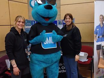 Lara and Alison stand next to a person in a giant blue bear mascot costume