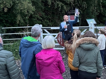 Adam shows a picture of a bat to a group of people on a guided walk