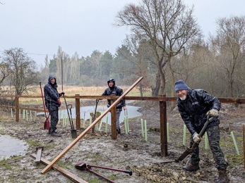 Adam, Dave and Sam digging in mud to install a new fence in the rain