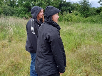 Two young woman standing in the rain looking to the right