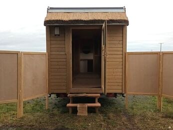 the open door into the wooden tiny house and information panels unfolded from the sides