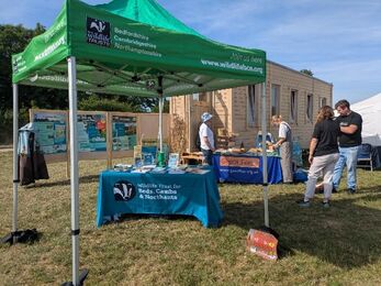 A Wildlife Trust branded gazebo and tables in front of the wooden tiny house