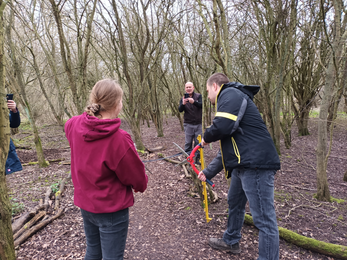Lewis holds red handled loppers to cut the ribbon opening the new path. 