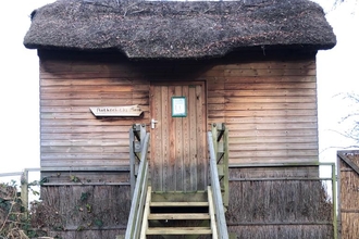 Newly replaced wooden steps leading up to a wooden hide with thatched roof