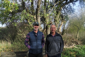 Andrew Cuthbert and Geoff Willis stand under an apple tree