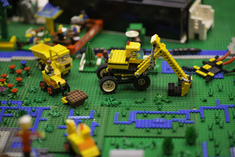 Digger and trucks made of Lego on a Lego wetland