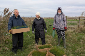 Sharon Hearle with volunteers Ken and Danica with cardboard trays of plug plants