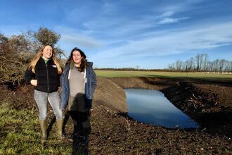 Ellen and Kaitlyn stand by a large newly-dug pond