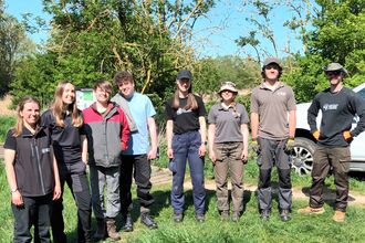 8 people in outdoor workwear stand in a sunny nature reserve