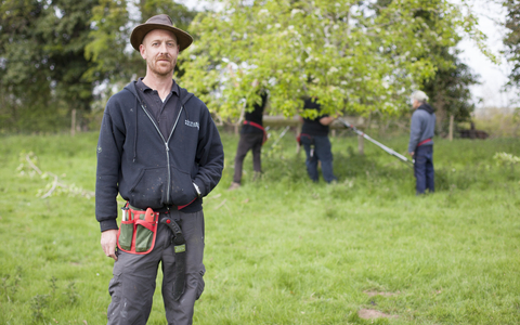Laurence standing in an orchard