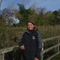 Lady in Wildlife Trust jacket leaning on fence in front of reeds