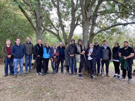 Group of adults standing side by side in a line under trees