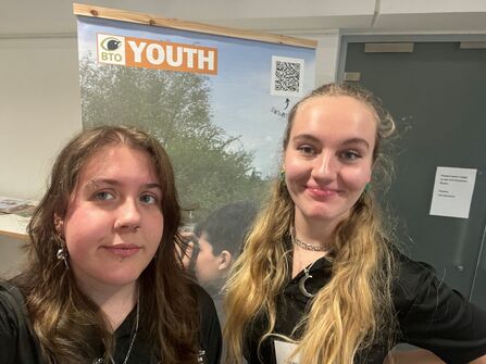 Katie and Kaitlyn take a selfie in front of a BTO Youth roller banner
