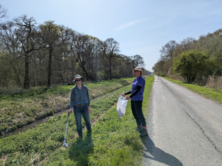 Two women litter picking along a road in a nature reserve