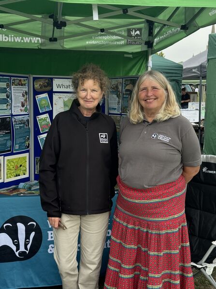 Kate and Catherine wear Wildlife Trust tops and stand at a Wildlife Trust information stand