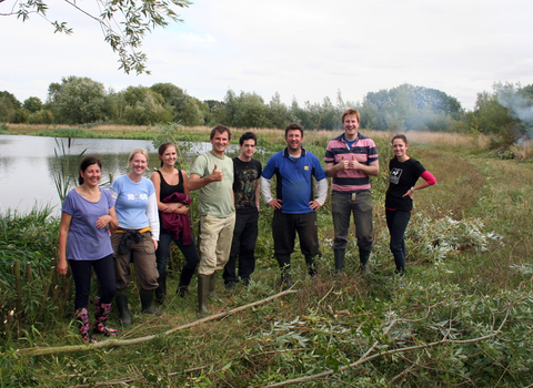 Group of smiling adults looking to camera standing in front of lake