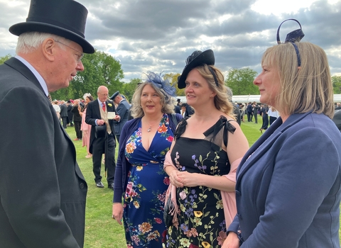 The Duke of Gloucester in top hat and tails, speaks with three ladies at a royal garden party