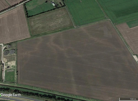 Google Earth image of lighter patterns of soil seen in a dark brown field